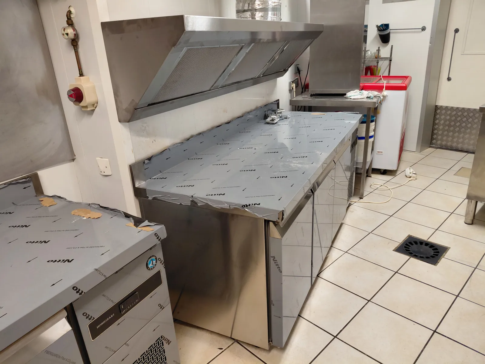 Tables réfrigérées inox installées sous une hotte par CFC 29 dans une cuisine collective