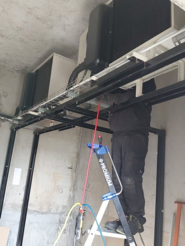 Frigoriste CFC 29 sur un escabeau, manomètres branchés sur des groupes frigorifiques
