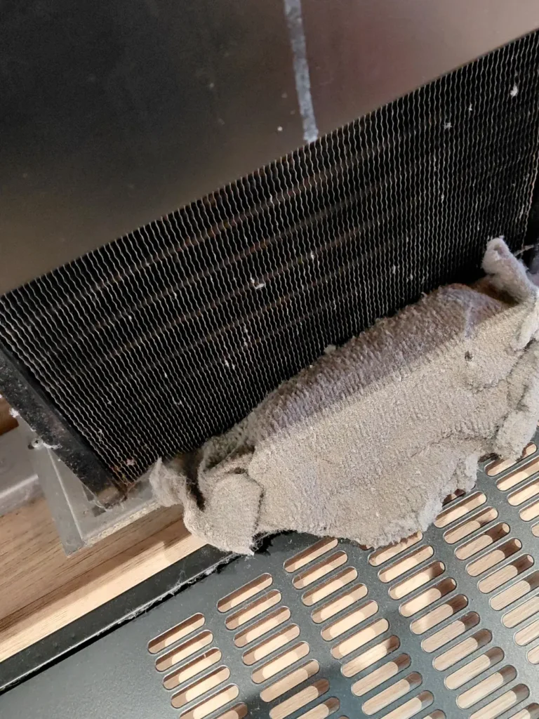 Condenseur de meuble frigorifique et la plaque de poussière qui le recouvrait, retirée lors d’une visite de maintenance